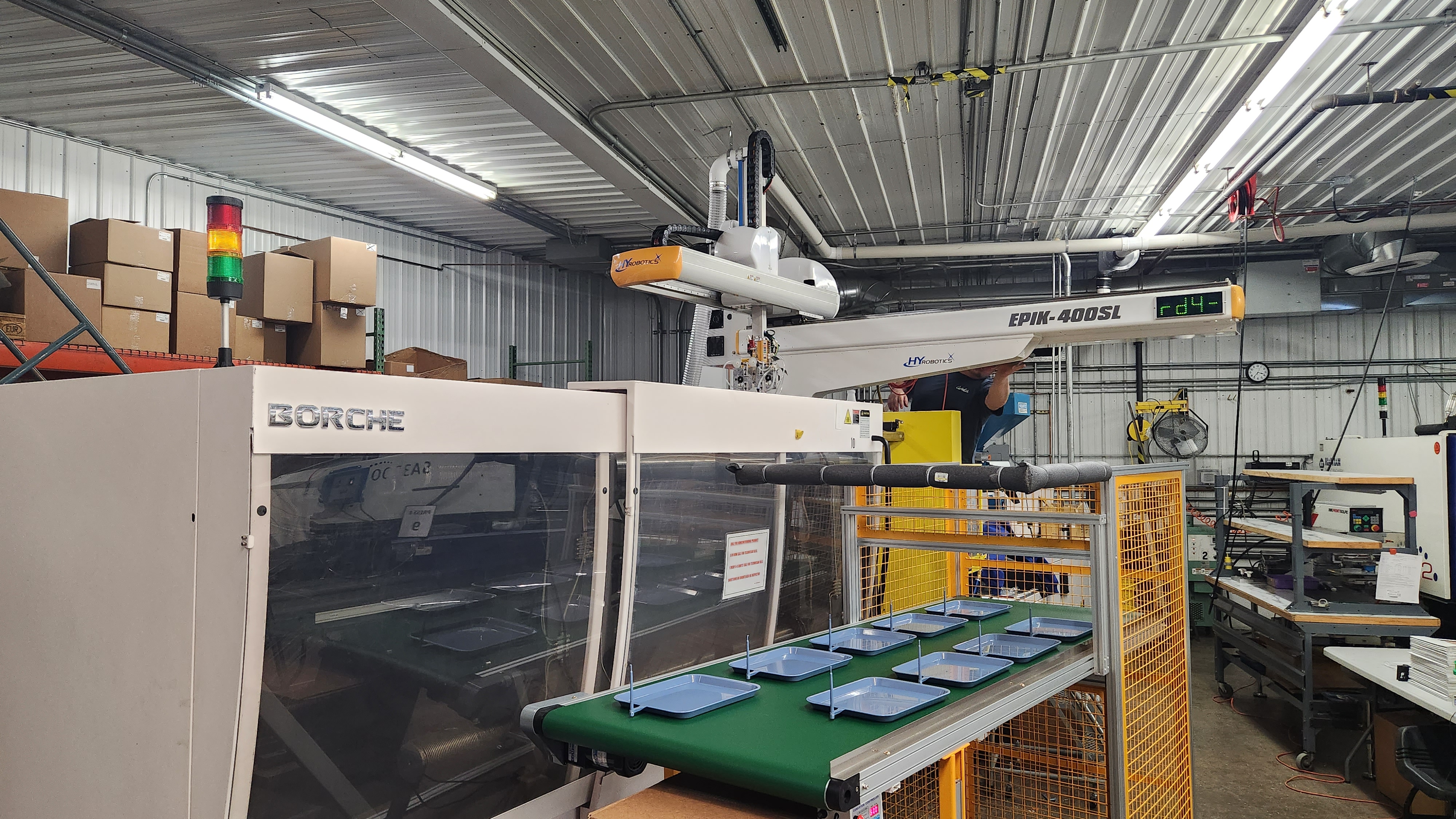 Industrial injection molding machine with robotic arm on a factory floor