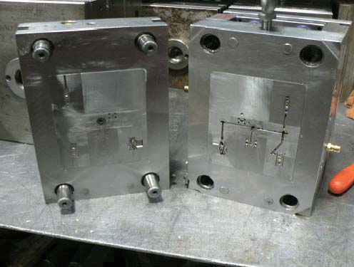 Two-plate injection mold open on a press showing the core and cavity structure