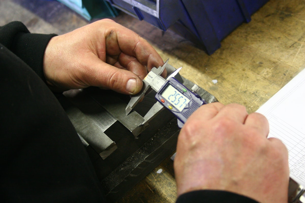 Engineer using digital calipers to measure a precision injection-molded plastic component during dimensional quality inspection